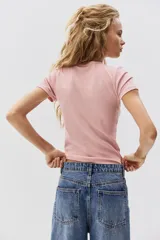 Remera de manga corta, color rosado, con textura de punto acanalado y cuello redondo ribeteado.