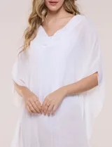 Vestido playero tipo túnica de corte holgado color rosado, confeccionado en tejido semi transparente con textura sutilmente arrugada. Cuenta con escote en V pronunciado, mangas estilo kimono de caída fluida y aberturas laterales en el ruedo irregular.