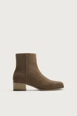 Bota corta de piel con acabado de serraje, diseño de horma cuadrada y tacón bloque de madera. Cuenta con cierre de cremallera lateral.