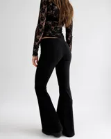 Pantalón Oxford de crepe elastizado color negro, de corte entallado en la parte superior y acampanado en las pantorrillas, con bolsillos traseros.