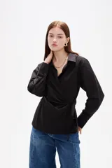 Camisa blanca de algodón con diseño cruzado y anudado lateral, cuello camisero y mangas largas con puños.