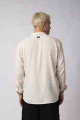 Camisa de manga larga con cuello clásico y cierre frontal de botones. Presenta un calce relajado y una textura liviana.