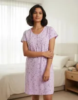 Camisón de manga corta en color lila con estampado de flores y corazones pequeños. Presenta cuello redondo con tapeta de botones y ribete decorativo.