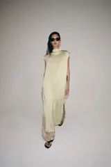 Vestido midi de Zara Woman Collection confeccionado en hilatura de viscosa con tejido satinado, de color beige. Presenta cuello subido, diseño sin mangas (manga sisa), bajo recto con aberturas laterales y cierre en la espalda con alamares.