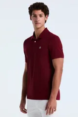 Polo de manga corta en color bordó, confeccionada en tejido piqué de algodón. Presenta cuello clásico, cierre frontal con dos botones y el logo de la marca bordado en el pecho.