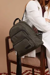 Mochila urbana de diseño funcional en color beige, confeccionada en tela impermeable. Cuenta con un compartimento principal amplio, un bolsillo secundario y un bolsillo frontal, todos con cierre. Incluye asa superior y correas ajustables para los hombros, con detalle de etiqueta de marca en el frente.