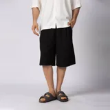 Bermuda sastrera gris de corte baggy, con pinzas al frente y diseño holgado que se extiende por debajo de la rodilla.