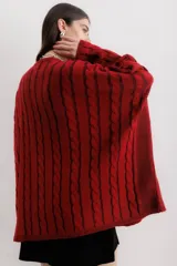 Sweater tejido de punto color fucsia con diseño de trenzas verticales en color naranja. Tiene cuello redondo y dos bolsillos frontales.