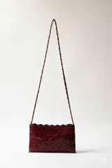 Cartera rectangular de diseño estructural color bordó, hecha a mano, con textura en capas y correa larga para llevar al hombro o cruzada.