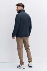 Sweater de punto acanalado en color marrón oscuro, con cuello alto y cierre frontal de cremallera parcial. Presenta mangas largas y puños ajustados.