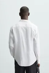 Camisa de corte regular fit confeccionada en tejido de lino, con cuello solapa, manga larga con puños abotonados y cierre frontal de botones.