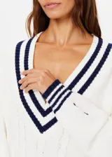 Sweater de punto color blanco con escote en V profundo y rayas azul marino en cuello, puños y dobladillo.