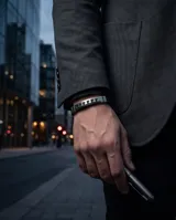 Pulsera masculina de diseño moderno, compuesta por una banda central de acero inoxidable con patrón geométrico estilo griego y laterales de goma negra.