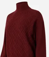 Suéter de manga larga confeccionado en tricot, con cuello alto y diseño de bordado de rombos en relieve. Presenta puños y ruedo acanalados.