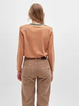 Remera de manga larga con cuello redondo y estampado a rayas horizontales en tonos marrón y negro. Tiene un logo bordado en el pecho de color rojo.