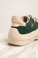 Zapatillas deportivas de gamuza verde con detalles en cuero color crema, cordones blancos y suela chunky color crema.