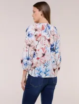 Blusa de gasa liviana blanca con estampado floral en tonos azules y rosados, escote en V, mangas 3/4 abullonadas con puños elásticos y corte fluido.