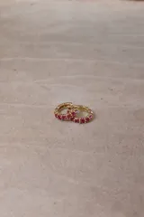 Aros tipo argolla pequeña de base metálica dorada con incrustaciones de cristales transparentes en la parte frontal.