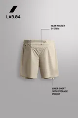 Short de running 2 en 1 color beige, confeccionado en tejido técnico ligero y elástico con malla interior integrada. Presenta cintura elástica ajustable con cordón, bolsillo trasero con cierre y aberturas laterales en el bajo.