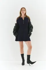 Vestido corto de punto acanalado en color azul marino, con escote redondo, tapeta de botones frontal, mangas largas, cuerpo entallado y falda con vuelo.