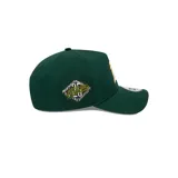 Gorro New Era verde oscuro con el logo de los Oakland Athletics bordado en blanco y amarillo en el frente, parche del 25 aniversario en el lateral y visera curva.