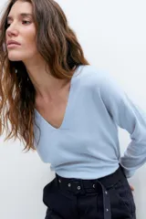 Sweater de tejido liso color celeste claro, con escote en V y mangas largas.