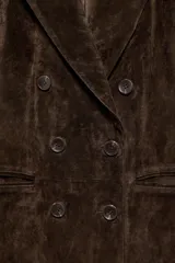 Blazer de ante color marrón, con cuello solapa, hombreras, manga larga y cierre frontal cruzado con botones. Cuenta con bolsillos delanteros de doble vivo.