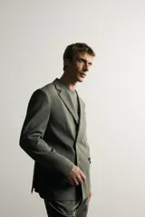 Blazer cruzada de traje color verde militar, de corte regular fit, con solapas de muesca, cierre frontal de doble botonadura, bolsillos con solapa en la cadera y bolsillo de vivo en el pecho.