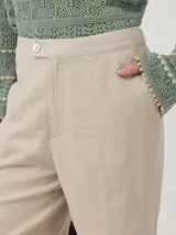 Pantalón de tiro medio color beige, confeccionado en mezcla de lino y viscosa. Presenta un corte recto con aberturas laterales en el bajo y cierre frontal con botón.