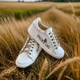 Championes urbanos de cuero marfil con cordones beige y la firma de Carolina De Cunto pintada a mano en el lateral.