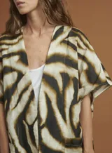 Chaqueta tipo kimono con estampado animal print de cebra en tonos marrón y negro. Tiene mangas 3/4 con bolsillos de parche y está confeccionada en lino.