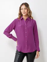 Camisa de satén color violeta, con cuello clásico, cierre frontal con botones, manga larga con puños anchos abotonados y bolsillo aplicado en el pecho.