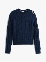 Sweater de punto con diseño de trenzas, cuello redondo y detalle de botones dorados en el hombro. Presenta terminaciones acanaladas en puños y dobladillo, con logo bordado en el pecho.