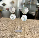 Aros colgantes con forma de flor hechos de nácar con detalles dorados.