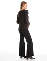 Buzo de tejido soft color gris oscuro, con cuello redondo y mangas largas. Presenta hombros con diseño plisado y detalle de perlas aplicadas.