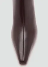 Botín de cuero caprino color marrón oscuro, con diseño de punta fina y tacón kitten de 6,5 cm. Presenta cierre de cremallera lateral.