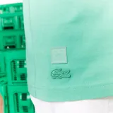 Remera verde con estampado del logo de Lacoste pixelado al estilo Minecraft y el logo de Minecraft debajo.