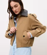 Campera Comfort de poliéster color camel, con cuello de poliuretano en contraste color marrón oscuro, cierre frontal y bolsillos con solapa y botones. Presenta martingalas en los hombros y elástico en la cintura.