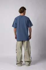 Remera oversize de algodón pesado color azul, con bordado "HUMAN" centrado en el pecho y hombros ligeramente caídos.