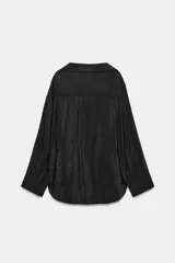 Camisa de corte amplio y fluido con cuello solapa, manga larga con puños abotonados y bolsillo de plastrón en el delantero. Presenta cierre frontal con botones y un acabado satinado.