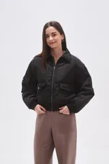 Campera tipo bomber color negro, con cierre frontal, cuello camisero, bolsillos frontales con solapa y puños elásticos.