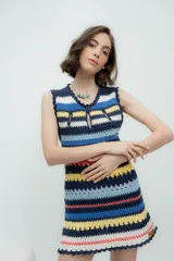 Vestido corto tejido a crochet con rayas horizontales en colores azul, amarillo, marrón, blanco y rosa. Presenta escote redondo con abertura en forma de gota y terminaciones con puntilla.