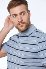 Remera polo celeste con rayas horizontales en azul marino y blanco, confeccionada en tejido piqué. Tiene botones personalizados y logo bordado en el pecho.