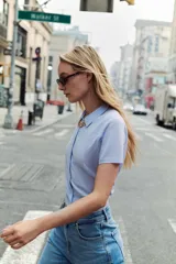 Chaqueta de punto celeste, de manga corta, con cuello solapa y cierre frontal con botones.