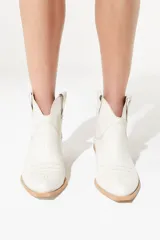 Botas de cuero vacuno color negro con caña baja bordada a tono, tacón bajo, punta alargada redondeada y suela cuadrada.