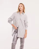 Camisa gris claro oversized de algodón, con botones frontales a tono y vivos blancos ondulados en el frente.