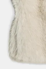 Chaleco Zara de pelo sintético en color beige, con diseño abierto, manga muy corta y cierre lateral con clip.