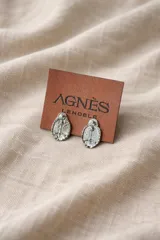 Aros tipo botón con diseño ovalado y relieve del escudo, marca Agnès Lenoble.