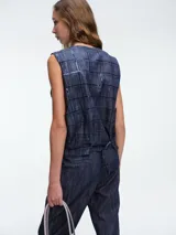 Chaleco sastrero de denim negro con diseño de cuadros y aplicación de lentejuelas sutiles. Presenta escote en V, cierre frontal con botones metálicos y bolsillos delanteros.
