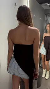 Top negro de diseño asimétrico tipo strapless, con drapeado lateral y detalle de hebilla metálica plateada.